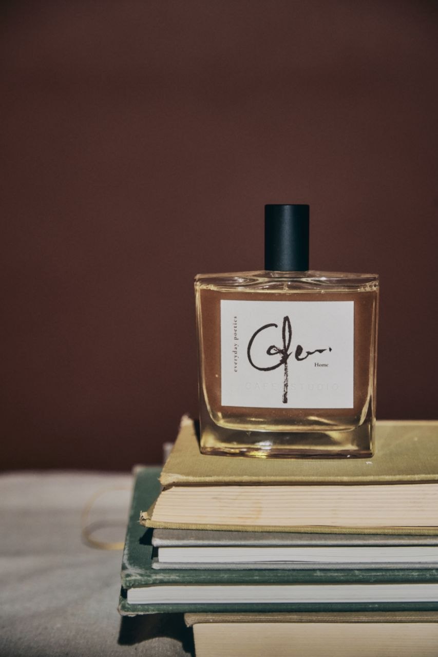 Everyday Poetics fragrance bottle on a stack of books with a brown background.