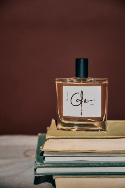 Everyday Poetics fragrance bottle on a stack of books with a brown background.